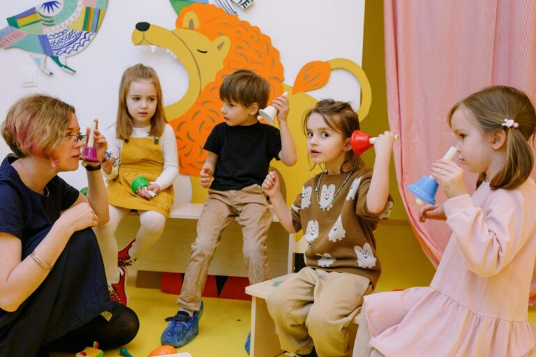 A teacher and her students holding differently coloured bells in the concept of schools in Chiswick.