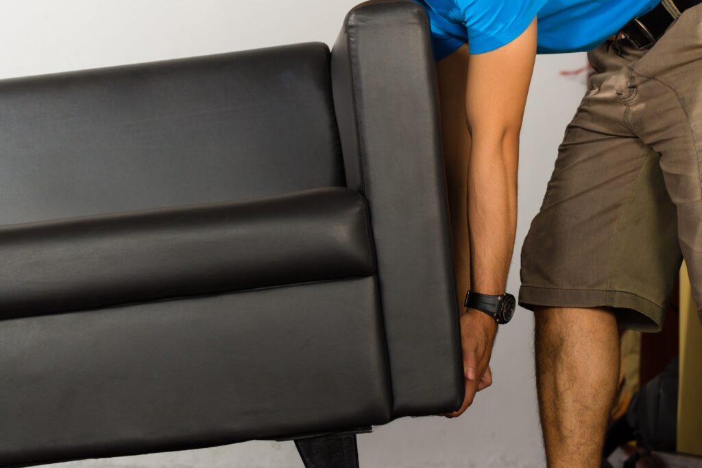 Cropped image of a man lifting a leather sofa