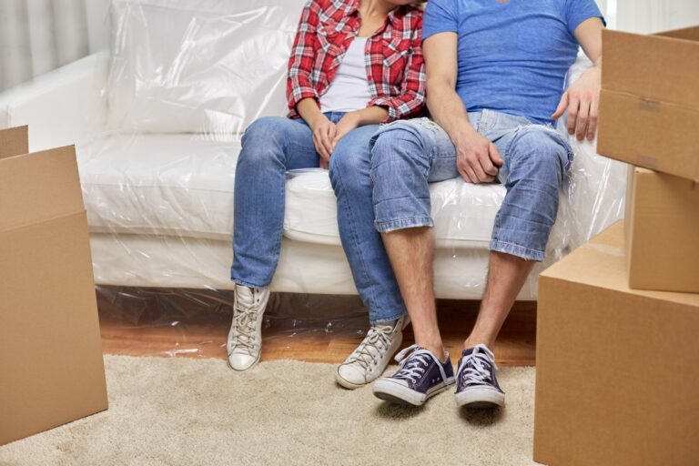 Cropped image of a couple surrounded by packing materials after the move in the concept of 'What to Do with Packing Materials After Moving House'.