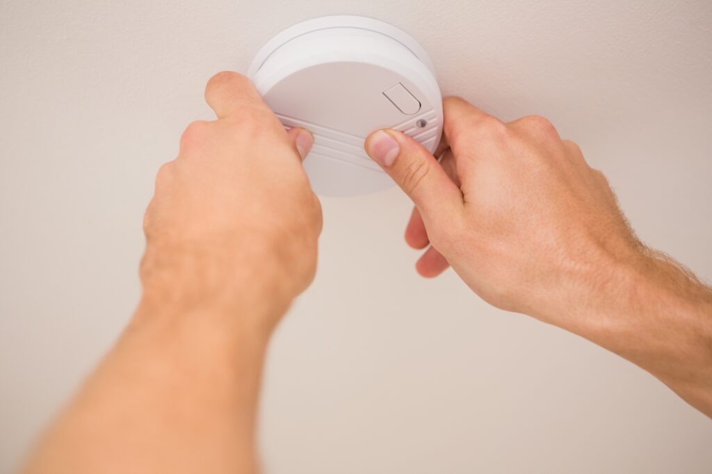 A cropped image of a man's hands installing the smoke detector