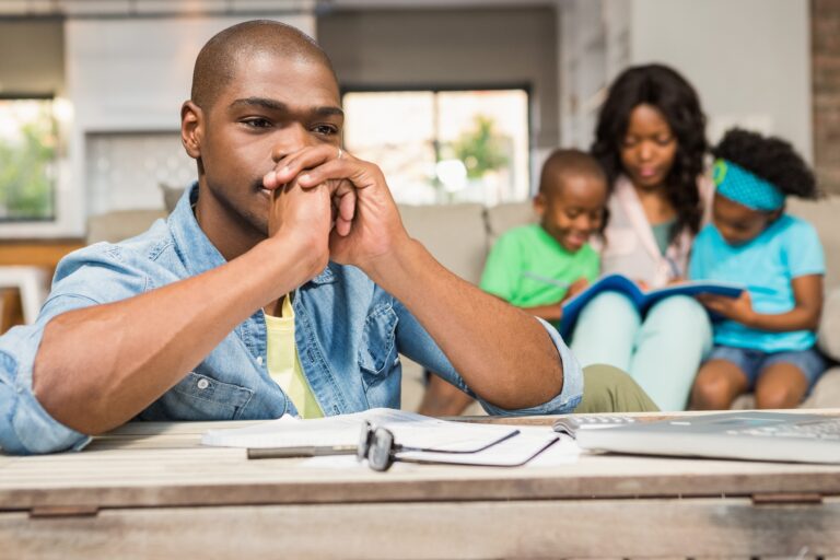 A young father thinking of house removals cost while his family is sitting on the couch
